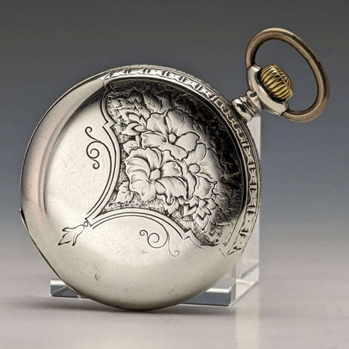 Reloj de bolsillo antiguo Leonidas de fabricación suiza, con caja de plata tipo saboneta grabada con motivos florales, en buen estado de funcionamiento.