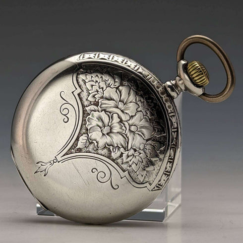 Reloj de bolsillo antiguo Leonidas de fabricación suiza, con caja de plata tipo saboneta grabada con motivos florales, en buen estado de funcionamiento.