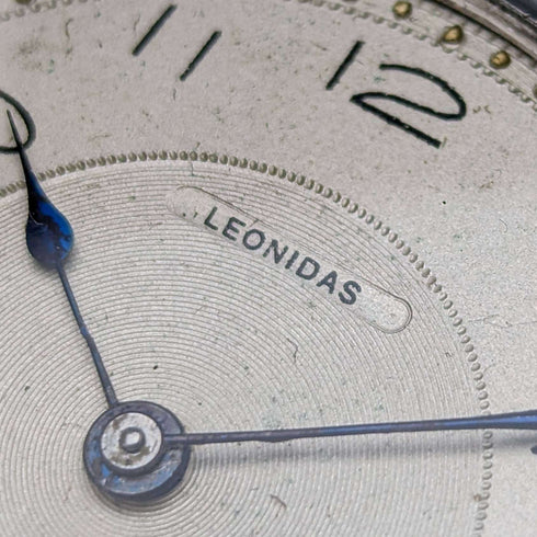 Reloj de bolsillo antiguo Leonidas de fabricación suiza, con caja de plata tipo saboneta grabada con motivos florales, en buen estado de funcionamiento.