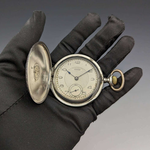 Reloj de bolsillo antiguo Leonidas de fabricación suiza, con caja de plata tipo saboneta grabada con motivos florales, en buen estado de funcionamiento.